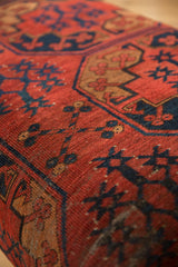 Close-up of the antique Ersari rug fragment's bold red and navy geometric pattern on the ottoman table.