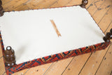 Ottoman underside with white canvas, copper studs, antique Ersari rug edge, and ONH studio tool.