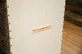 Ottoman underside with cream cotton canvas, brass tacks, and Old New House brand tag.