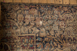 Aged texture of early 20th century Kerman rug fragment with wear and visible foundation.