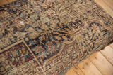 Worn antique Persian rug ottoman detail, visible foundation, knothead wear, beige and blue patterns.