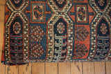 Curved edge of Vintage Rug Fragment Ottoman with geometric Northwest Persian pattern in navy and red.