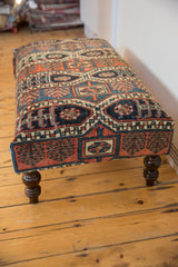 Geometric Northwest Persian pattern detail on rug fragment ottoman in reds, blues, and teal.