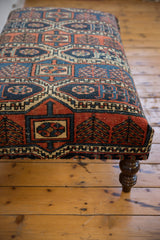 Geometric red, teal, navy motifs of the Northwest Persian rug fragment and turned leg.