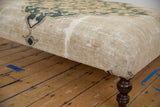 Antique Persian rug ottoman side, showing historic faded navy motifs and textured foundation.