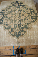 Antique Persian rug ottoman with dusty navy and beige square medallion design, showing historic patina.