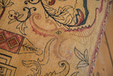 Intricate ivory, cochineal red, and charcoal motifs on antique Persian Kerman rug fragment, showing wear.