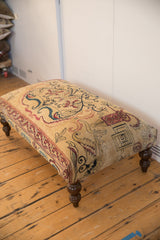 Antique Persian rug fragment ottoman featuring circa 1915 lantern and dragon motifs, dark carved leg.
