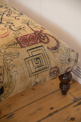 Antique Persian rug fragment ottoman corner, beige, red, charcoal patterns with turned wood leg.