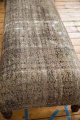 Distressed vintage Persian rug fragment surface with muted charcoal, beige, and textured wear showing foundation.
