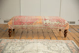 Vintage Rug Fragment Ottoman Table with distressed tangerine, dusty rose, ivory geometric patterns.