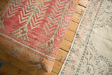 Distressed vintage Turkish rug fragment showing tangerine, dusty rose, and ivory zig-zag pattern.