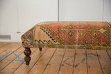 Curved wooden leg and distressed Oushak rug fragment upholstery with tribal patterns.