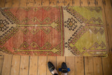 Distressed Oushak rug ottoman top, contrasting faded red and lime green geometric patterns.