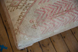 Distressed Oushak rug fragment pile in antique ivory, blush, and tan geometric motifs.