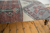 Distressed chestnut brown and silver gray geometric patterns on the vintage rug fragment ottoman.