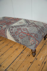 Distressed vintage Turkish rug fragment ottoman, showcasing unique geometric pattern and muted colors.