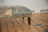 Distressed Oushak rug fragment with faded turquoise, ivory geometric design and carved leg.