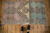 Distressed Oushak ottoman transition with geometric patterns in faded turquoise, antique ivory, lavender.