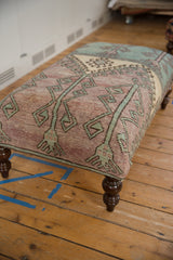 Distressed lavender and faded turquoise Oushak rug pattern on ottoman corner and leg.