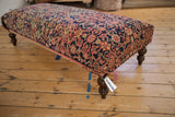 Corner view of vintage Persian rug ottoman, highlighting navy, blush, ivory hand-knotted motifs.