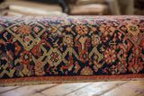 Close-up of intricate hand-knotted vintage Persian rug pattern in navy, blush, orange, ivory.