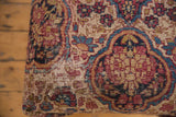 Antique Kerman rug fragment with visible foundation wear, beige, blue, and red floral motifs.