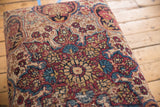 Antique Persian Kerman rug fragment upholstery detail with visible wear to foundation, beige, red, blue motifs.