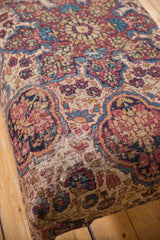 Worn antique Persian Kerman rug fragment revealing foundation texture, with traditional beige, blue, and red floral motifs.