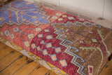 Vintage Turkish Oushak fragment, geometric patterns in purple, red, gold, green hues, with foundation wear.