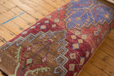 Detail of vintage Oushak fragment showing geometric patterns in raspberry red, blue, and brown.