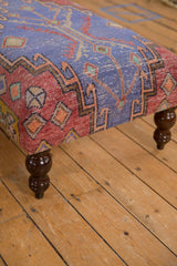 Dark brown turned wooden leg with a glossy finish on the vintage rug ottoman.