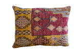Vibrant Oushak rug fragment pillow with golden yellow, magenta, blue, and brown geometric patterns.