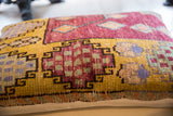 Vintage Oushak Rug Fragment Pillow with vibrant yellow, maroon, blue geometric patterns near edge.