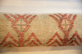 Vintage Oushak rug fragment close-up, red geometric pattern on beige pile.