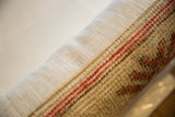 Vintage Oushak lumbar pillow's side showing red striped rug fragment texture and linen backing.