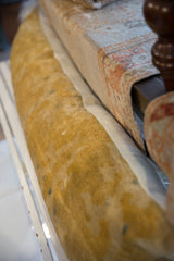 Faded gold antique Chinese rug fragment side of a lumbar pillow with muted patterns.