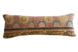 Vintage 1930s Khotan rug fragment lumbar pillow with muted pink, blue, and yellow geometric pattern.