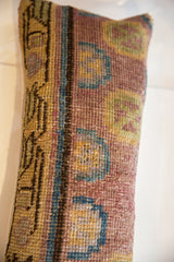 Hand-knotted vintage Khotan lumbar pillow texture showing geometric motifs in muted gold, blue, and rose.