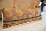 Textured weave of vintage Khotan lumbar pillow, with muted pink, blue, and yellow geometric motifs.