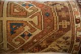 Antique Caucasian rug fragment pillow's coarse hand-knotted wool and geometric motifs.