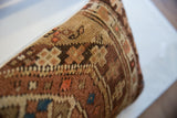 Close-up of the antique Caucasian rug fragment pillow's hand-knotted pile and earthy geometric pattern.