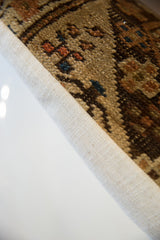Textured edge of the antique Caucasian pillow, showing hand-knotted brown, terracotta, and blue motifs.