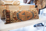 Side view of antique Caucasian pillow, showing rich brown border with intricate blue and terracotta geometric motifs.