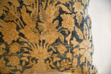 Storied texture and curvilinear floral pattern in golden ochre and deep indigo on antique Kerman fragment pillow.