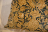 Antique Persian Kerman fragment pillow showcasing curvilinear floral motifs in golden-tan and muted blue.