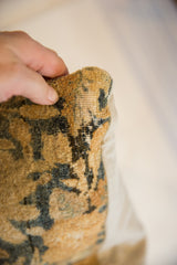 Hand holding antique Persian pillow corner, revealing textured golden and deep blue pile.