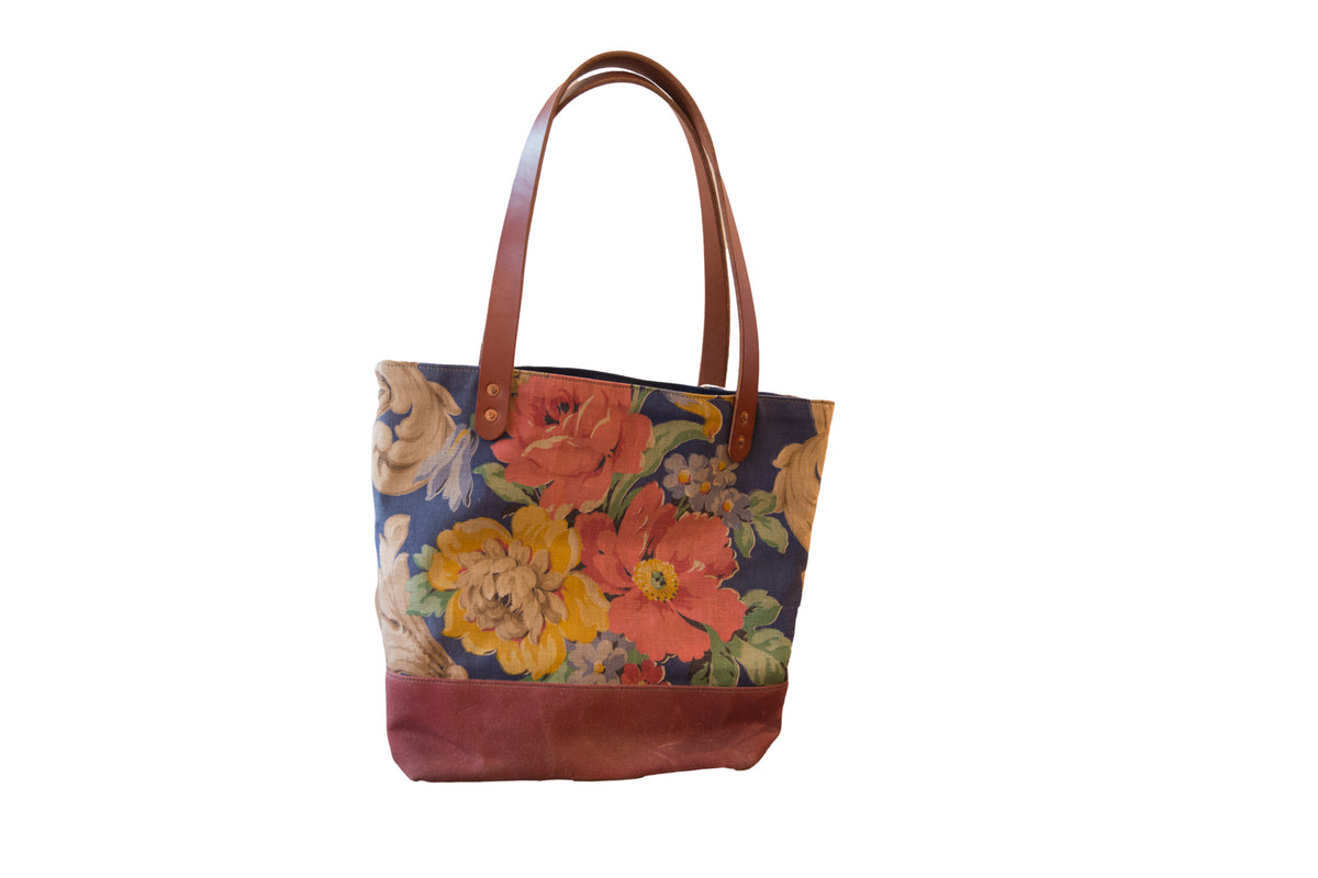 Vintage floral fabric market tote bag with blue, coral, yellow flowers and brown base.
