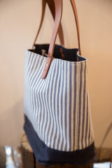 Brown leather straps and knotted rope closure on the striped market tote bag.
