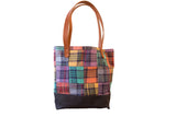 Vintage plaid patchwork market tote with a solid black base and brown leather handles.